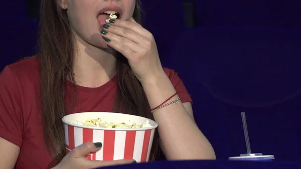 The young lady is eating popcorn during the screening — Stock Photo, Image