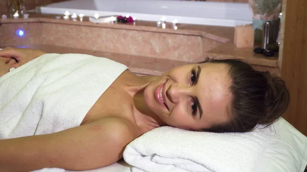 Una chica disfrutando de tratamientos de spa mira a la cámara y sonríe —  Fotos de Stock