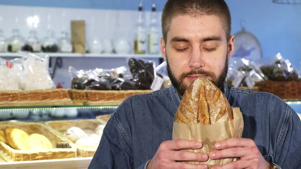 Close up of a cheerful man smelling freshly baked bread — Stock Photo, Image