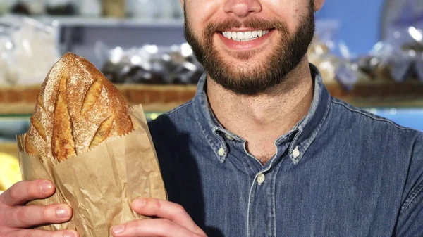 Улыбается бородач, держа буханку свежего хлеба. — стоковое фото