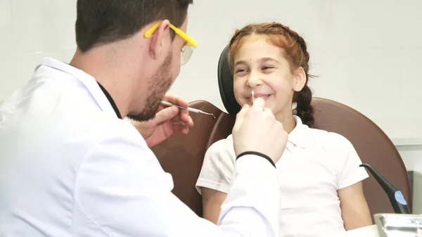 Um médico gentil examina os dentes de uma menina — Fotografia de Stock