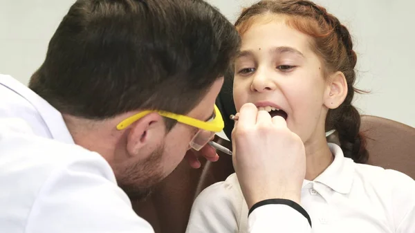 Um dentista atento examina seu pequeno paciente — Fotografia de Stock