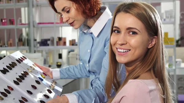 Felice giovane donna sorridente alla macchina fotografica scegliendo colore tintura per capelli con il suo parrucchiere — Foto Stock