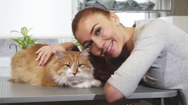 Prachtige vrouw die lacht poseren met haar kat op het kantoor van de dierenarts — Stockfoto