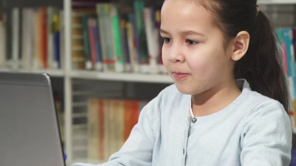 Närbild på en söt liten asiatisk tjej som skriver på den bärbara datorn — Stockfoto