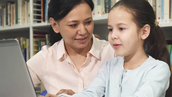 Mãe e filha felizes usando laptop enquanto estudam — Fotografia de Stock