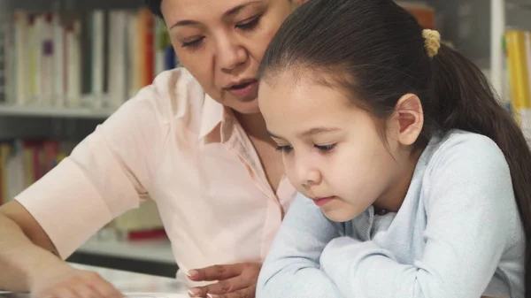 Close up of a cute little girl reading a book with her mother — Stock Photo, Image