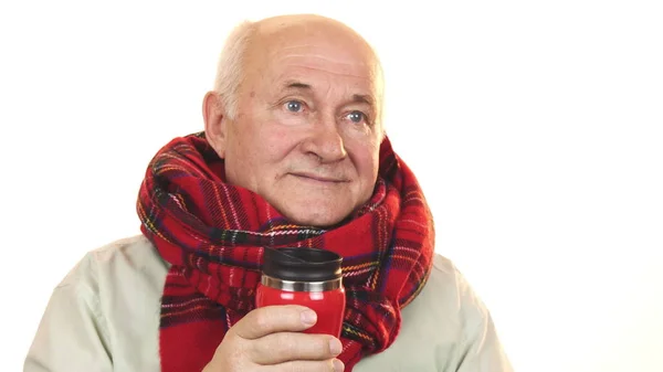 Hombre mayor alegre usando una bufanda sosteniendo termos sonriendo felizmente — Foto de Stock