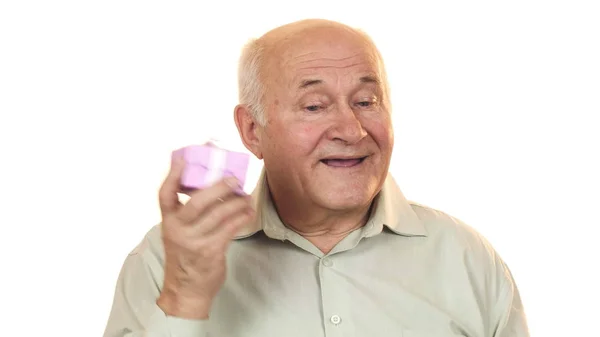 Happy grandpa smiling listening to a gift box guessing what is inside — Stock Photo, Image