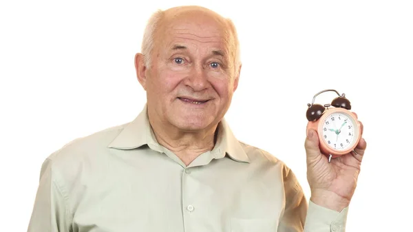 Yaşlı adam kameraya gülümseyen bir çalar saat bakarak — Stok fotoğraf