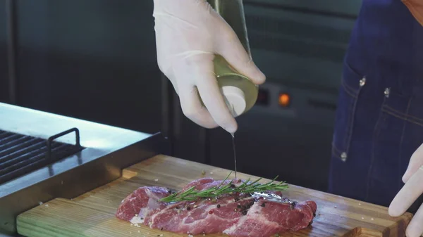 Colpo ritagliato di uno chef professionista che aggiunge olio d'oliva alla preparazione della carne di maiale — Foto Stock