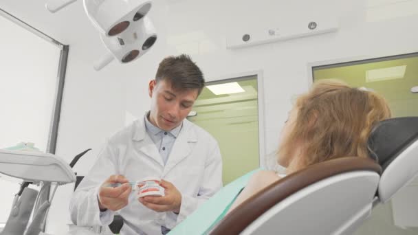 Jovem dentista do sexo masculino mostrando como escovar os dentes em um modelo dental — Vídeo de Stock