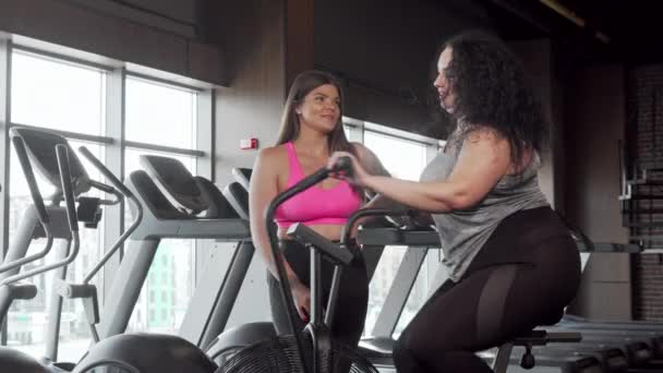 Charmig plus size kvinna leende till kameran tränar på luft cykel — Stockvideo