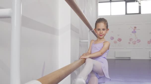 Vacker liten ballerina flicka som sträcker sig på balett bar på Dance School — Stockvideo