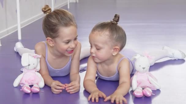 Две маленькие балерины, лежащие на полу в балетной школе отдыхающие после тренировки — стоковое видео