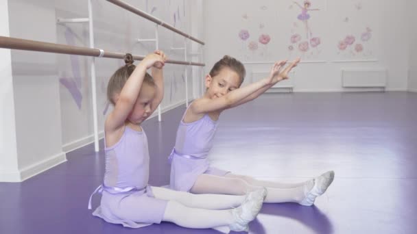 Schattige kleine ballerina's die samen op een dansschool aan elkaar uitrekken — Stockvideo