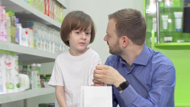 Hombre maduro de compras en la farmacia con su hijo pequeño — Vídeos de Stock