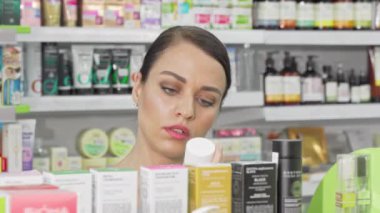 Güzel kadın eczanede raftan kozmetik ürünleri seçerek