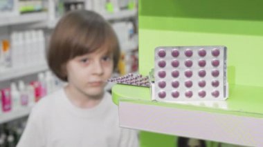 Küçük çocuk eczanede hap kabarcık inceleyen