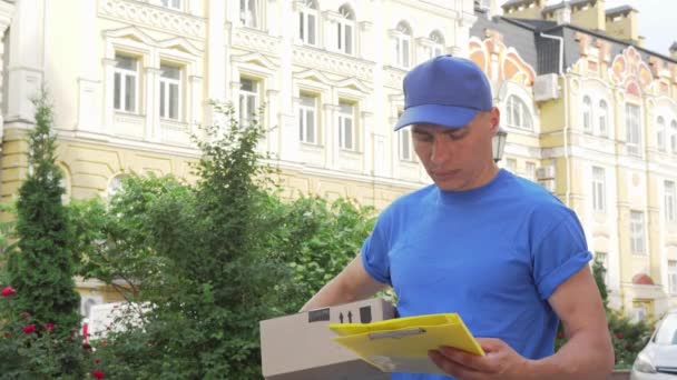 Delivery Guy med pappkartong söker hus mottagaren klient — Stockvideo