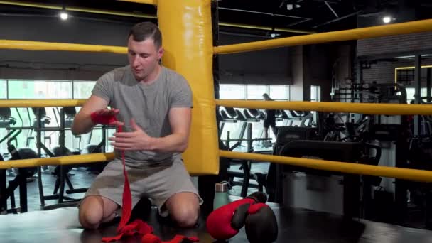 Boksa hazırlanan erkek dövüşçü yumruklarını bandajlarla sarmaya hazırlanıyor — Stok video