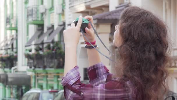 屋外で写真を撮りながらカメラに微笑む若い女性 — ストック動画