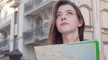 Bir harita kullanırken kameraya gülümseyen mutlu güzel kadın