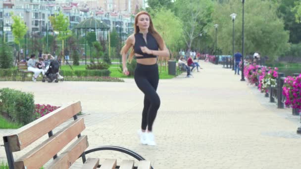 Preciosa mujer en forma descansando en el banco después de trotar — Vídeo de stock