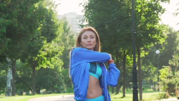 Beautiful sportswoman warming up before jogging in the park — Stock Video