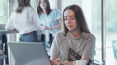 Neşeli genç kadın kahve dükkanında dizüstü bilgisayar üzerinde çalışan zevk