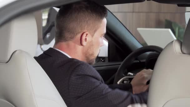 Vue arrière d'un homme d'affaires assis dans une nouvelle voiture chez le concessionnaire — Video