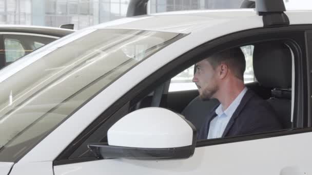 Счастливый красивый мужчина осматривает интерьер новой машины, сидящей внутри — стоковое видео