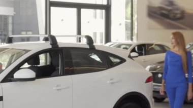Güzel kadın bayilik salonunda satın almak için otomobil seçimi