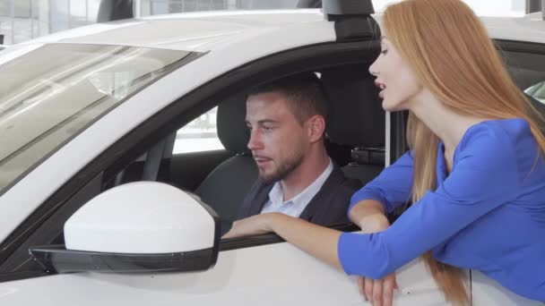 Knappe man praten met zijn vrouw terwijl het kiezen van nieuwe auto in dealer salon — Stockvideo