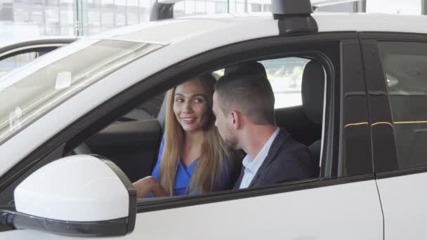 Vackert elegant par som sitter i en ny bil på återförsäljarfartyget — Stockvideo