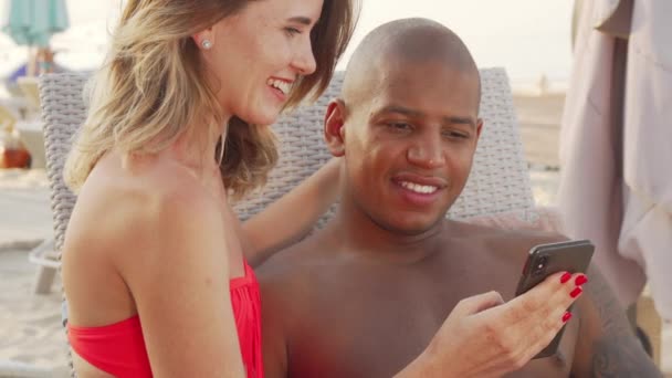Encantadora pareja multiétnica riendo viendo algo divertido en el teléfono inteligente — Vídeo de stock