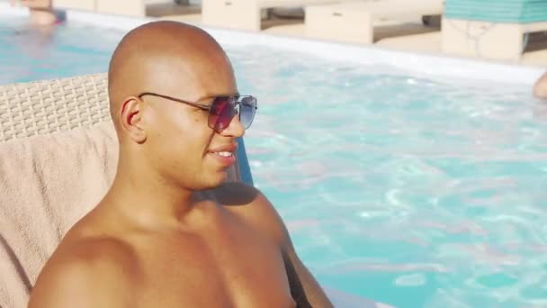 Relaxed handsome African man sipping his cocktail by the swimming pool — Stock Video