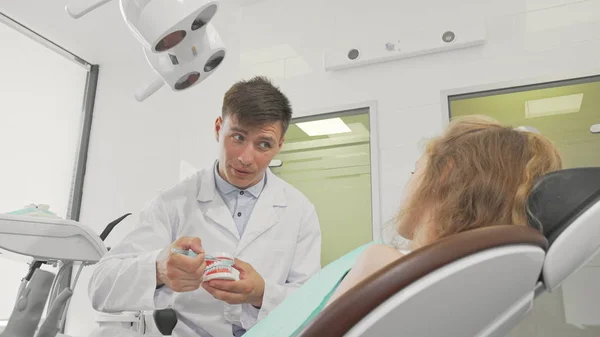 Jovem dentista do sexo masculino mostrando como escovar os dentes em um modelo dental — Fotografia de Stock