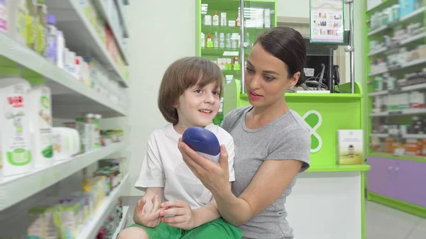 Adorabile bambino che parla con sua madre mentre fa shopping in farmacia insieme — Foto Stock