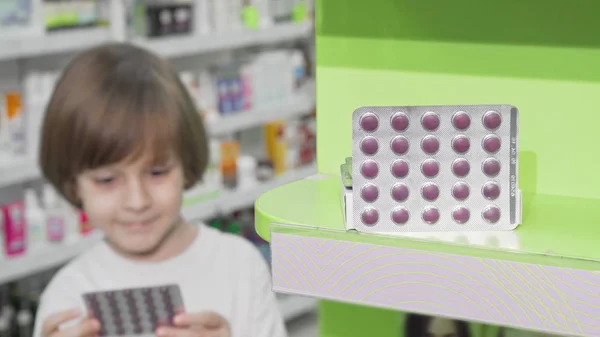 Menino examinando bolha de pílulas na farmácia — Fotografia de Stock