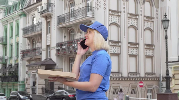 Женщина-курьер звонит клиенту, доставляющему пиццу в город — стоковое фото