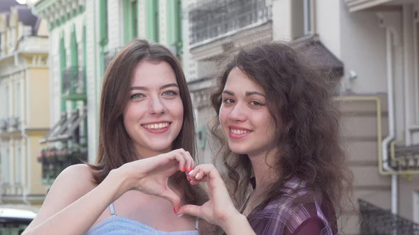 Happy two women showing heart shape with their hands