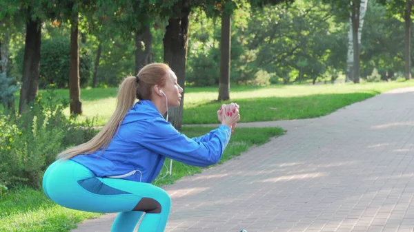 Спортивная женщина делает приседания на открытом воздухе по утрам — стоковое фото