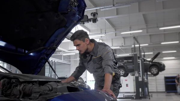 Технік автосервісу перевіряє масло в автомобілі з відкритим капюшоном — стокове фото