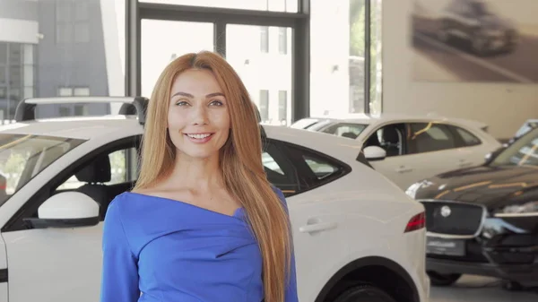 Hermosa mujer eligiendo automóvil para comprar en el salón de concesionarios — Foto de Stock