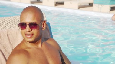 Rahat yakışıklı Afrikalı adam yüzme havuzu tarafından kokteylini yudumlarken