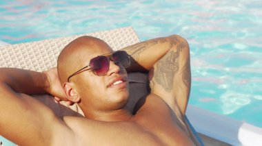 Havuz başında dinlenen mutlu bir Afrikalı adamın kırpılmış sürgülü çekim