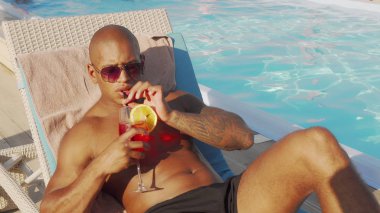 Yakışıklı Afrikalı adam havuz başında güneşlenme kokteyl içme