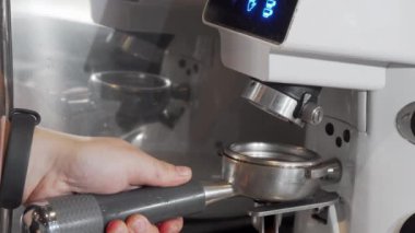 Kahve makinesinde kahve öğüten bir baristanın kırpılmış çekimi