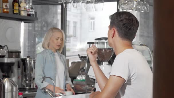 Przystojny młody człowiek uśmiechając się do kamery, podziwiając jego kawę w kawiarni — Wideo stockowe